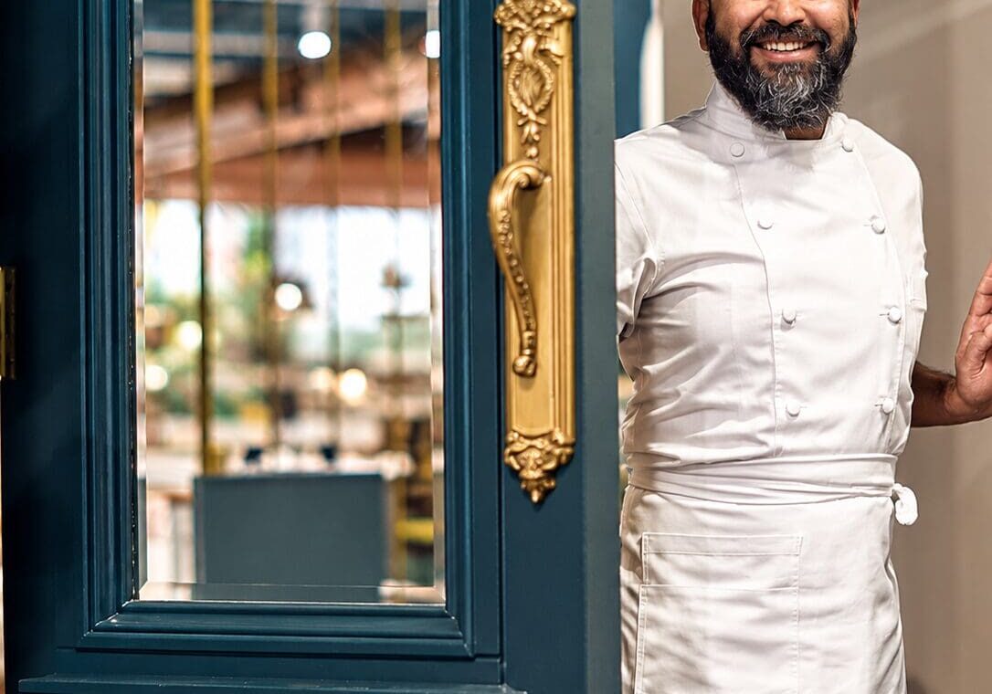 Smiling chef greeting guests at the entrance.